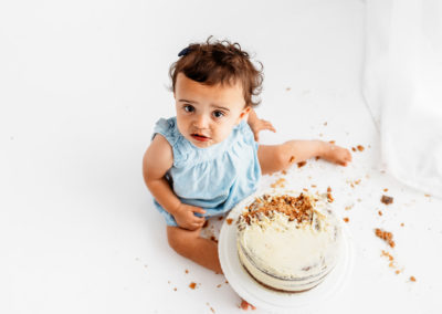 Cake Smash Photographer Barnsley, baby looking up at the camera wearing a blue dress