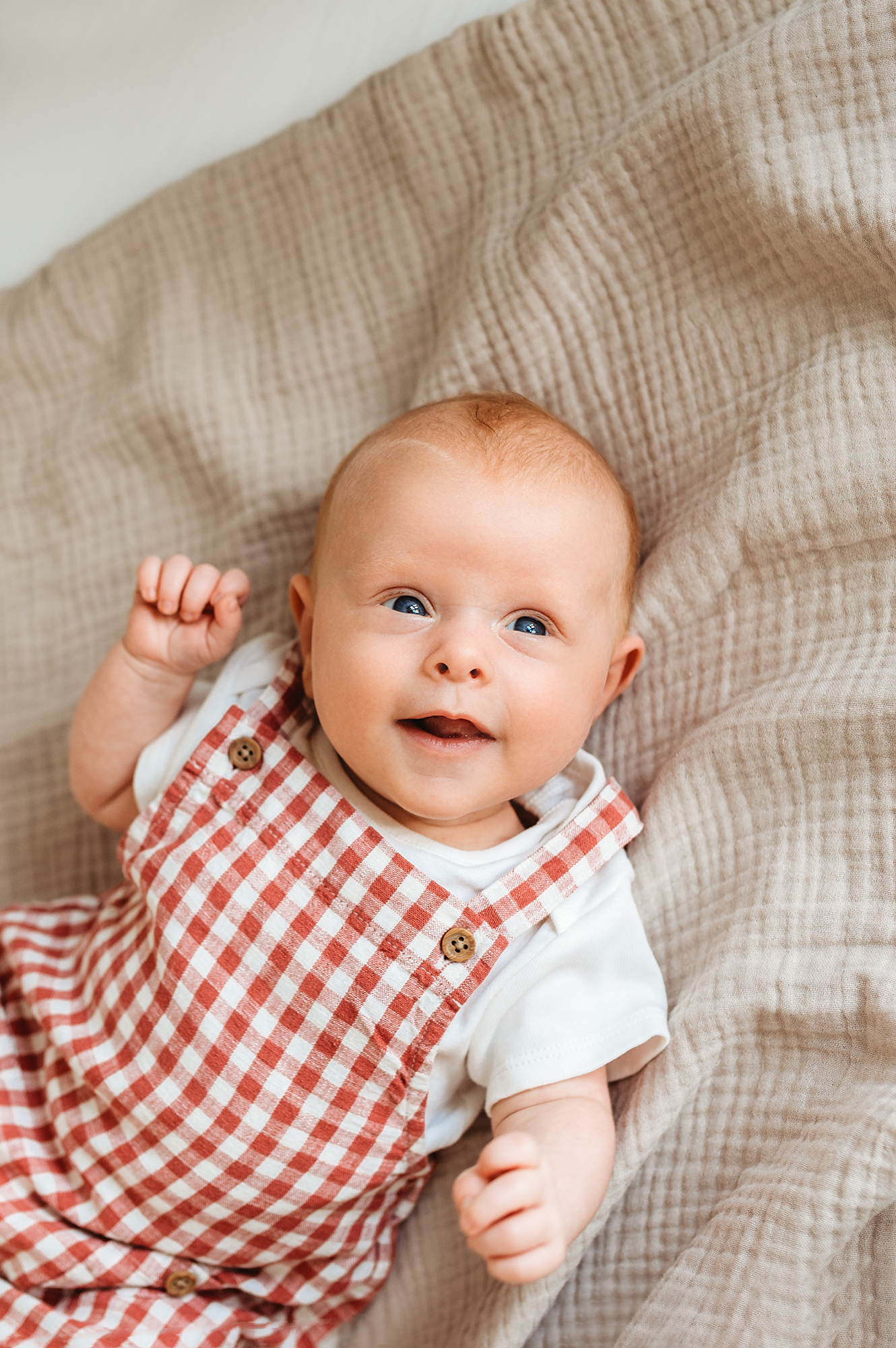 baby smiling in cot during lifestyle newborn photography session in Barnsley