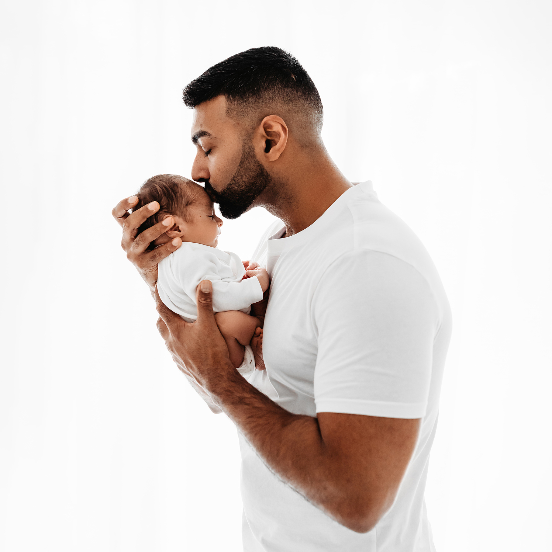 dad kissing baby all white studio
