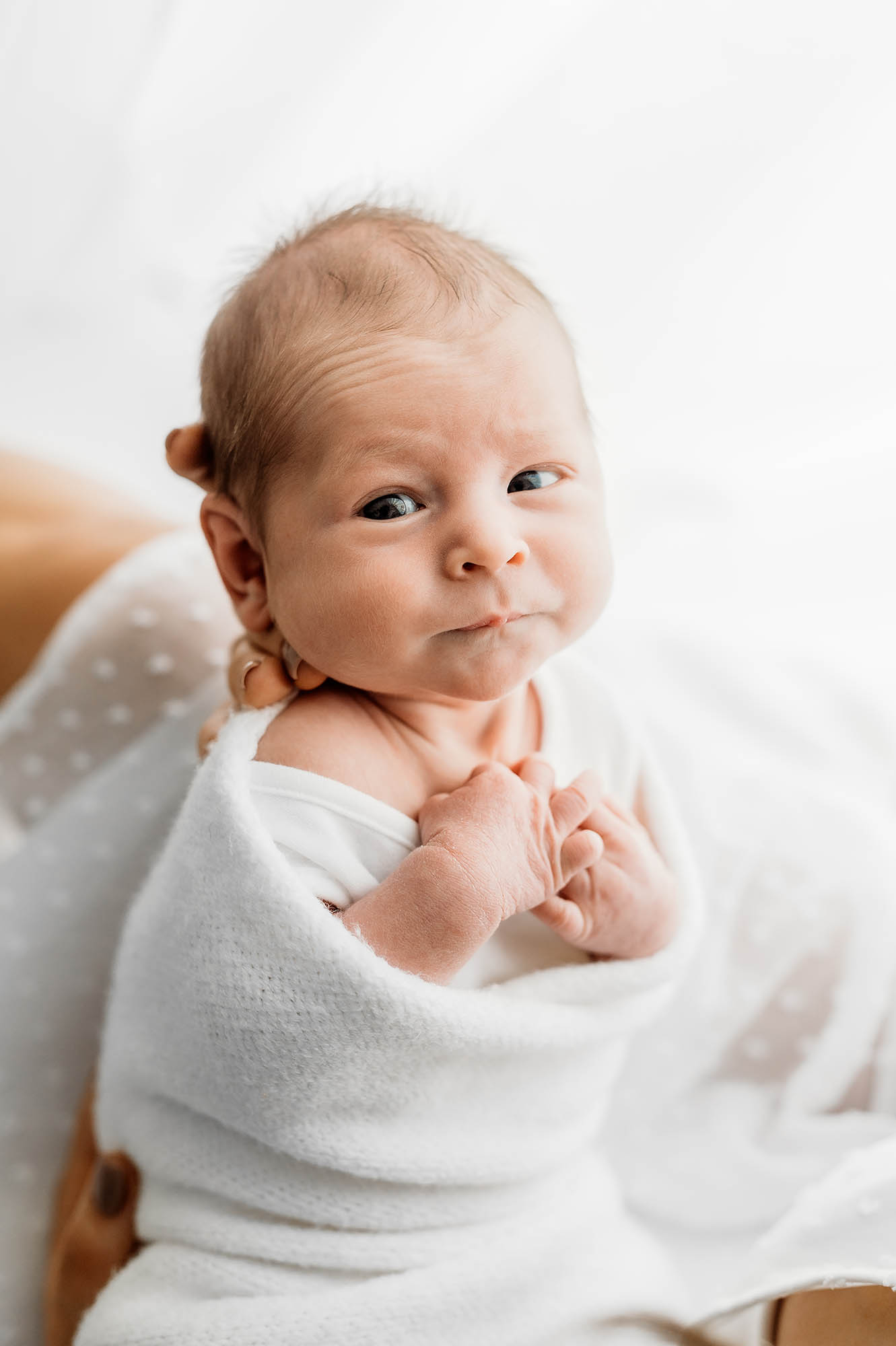 Baby cuddled and looking at camera with newborn photographer Barnsley