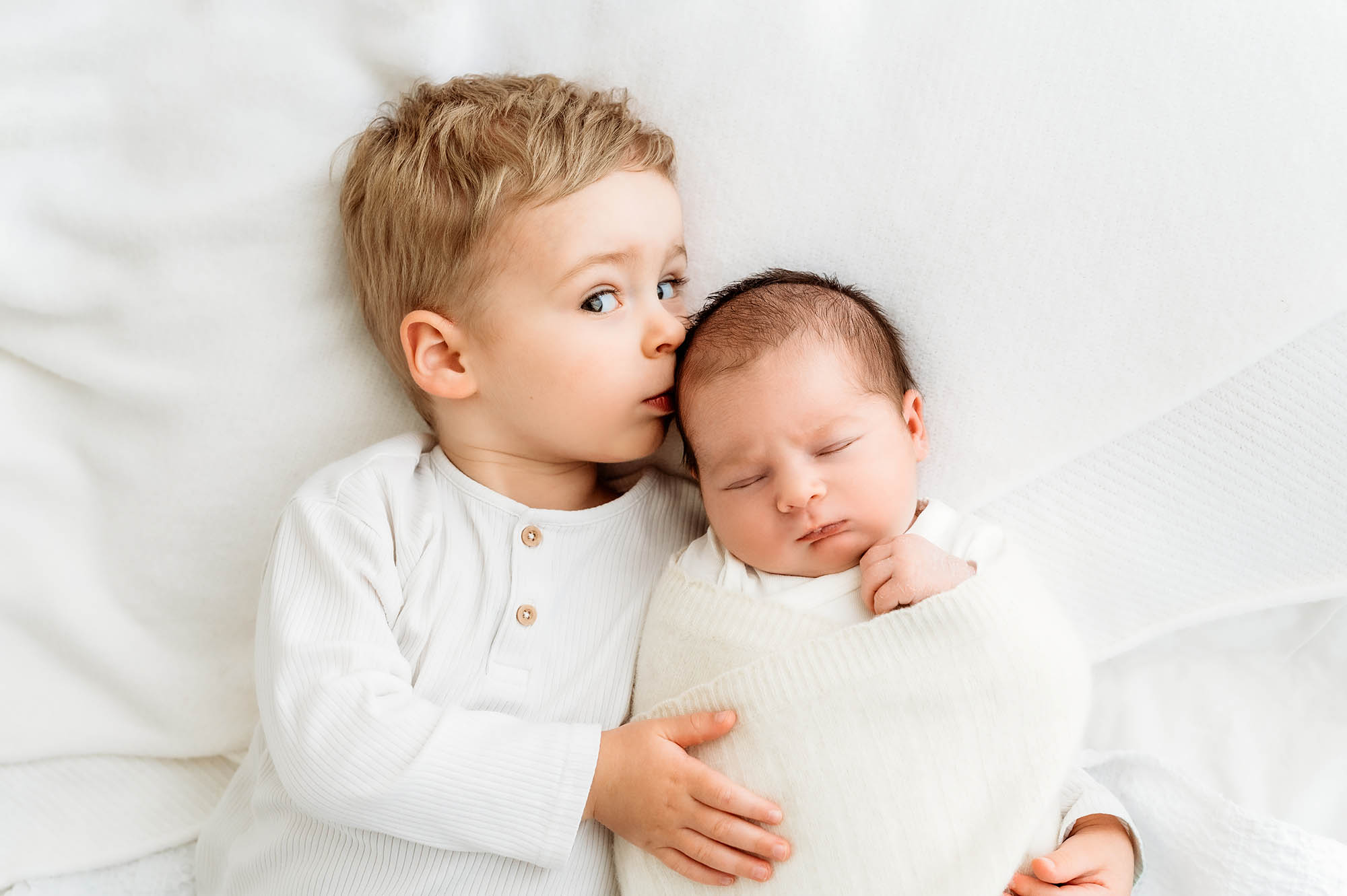 Brother kissing baby sister with newborn photographer Barnsley